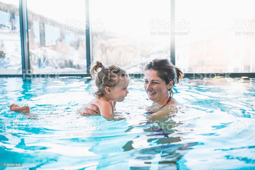 Mother holds up her daughter in a spa swimming pool