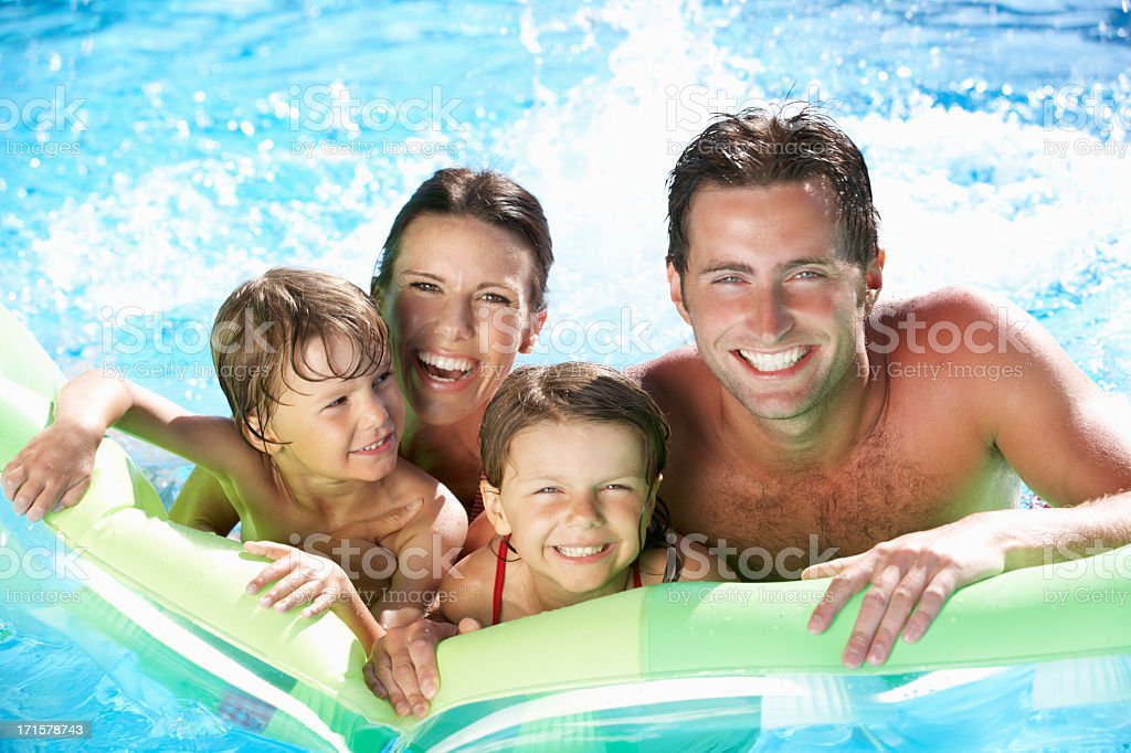 Family On Holiday In Swimming Pool Smiling To Camera.